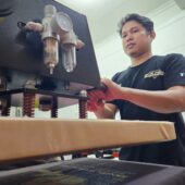 Masturi saat sedang mencetak baju kaos di rukonya/FOTO: AGUNG-GOSULSEL
